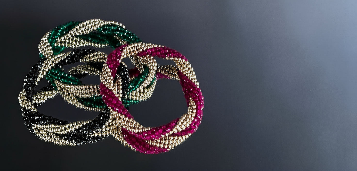 Three beaded bracelets in green, red, and gold on a dark background