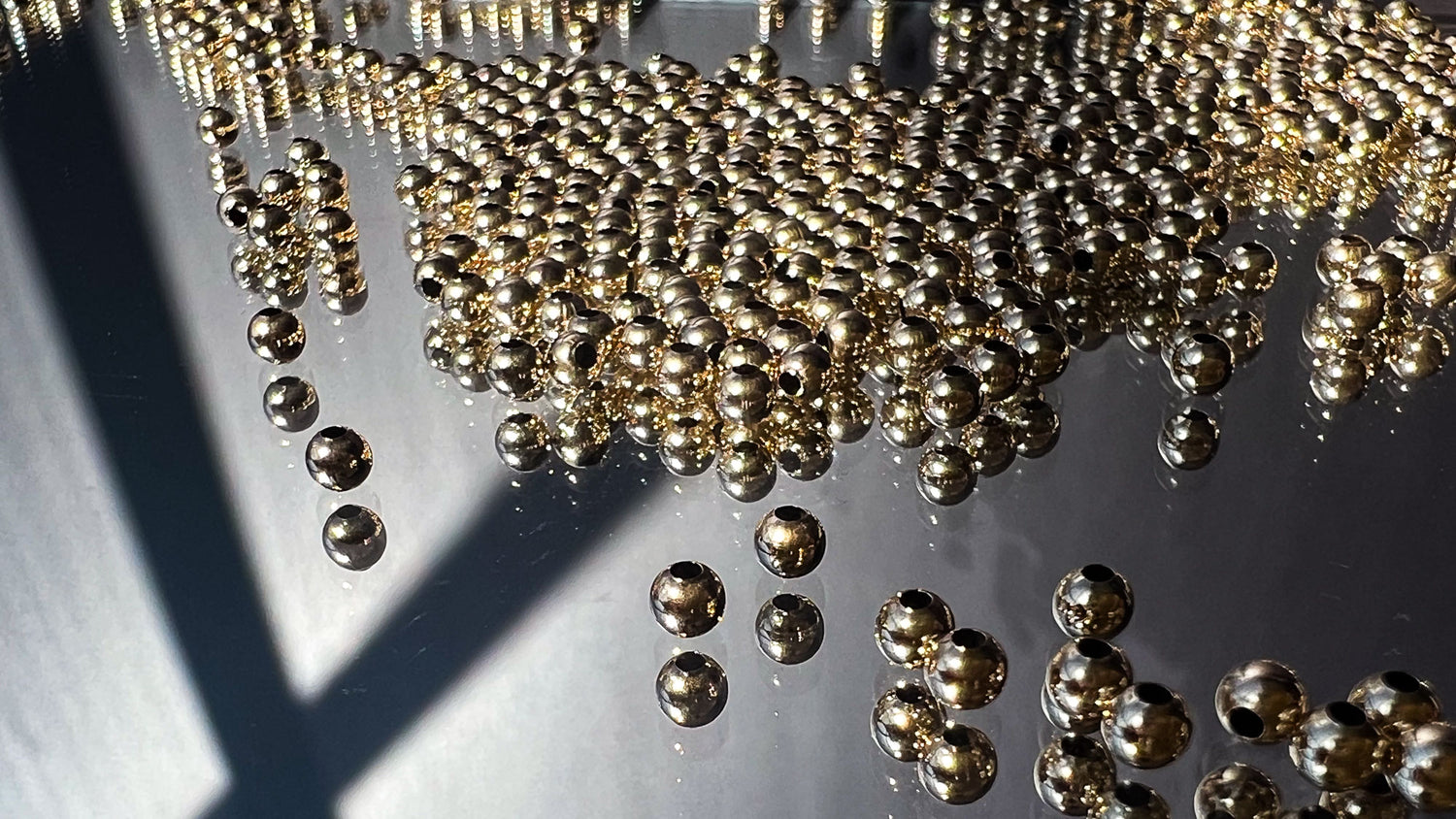 Gold metal beads scattered on a mirror
